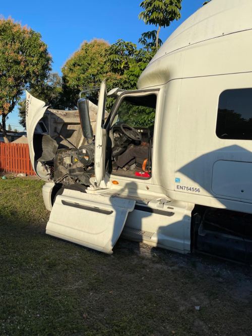 White semi truck with hood open being serviced on-site in a yard